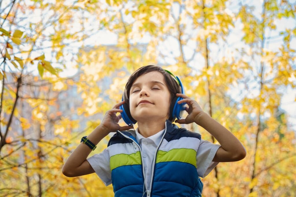 child listening to music in a park with trees in the background.