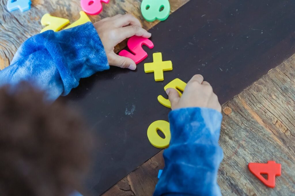 A child joyfully plays with vibrant plastic numbers on a wooden board, exploring shapes and colors.