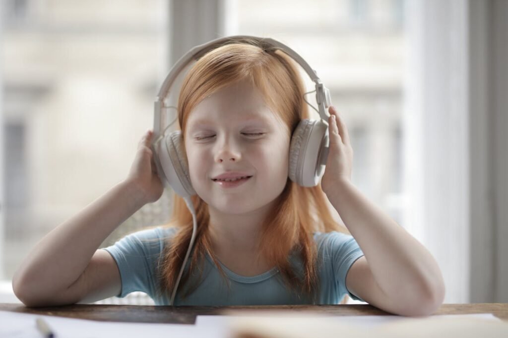 girl with headphones sitting at a table with her eyes closed.