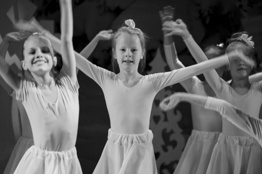  three girls in dresses are dancing together in a black and white photo.