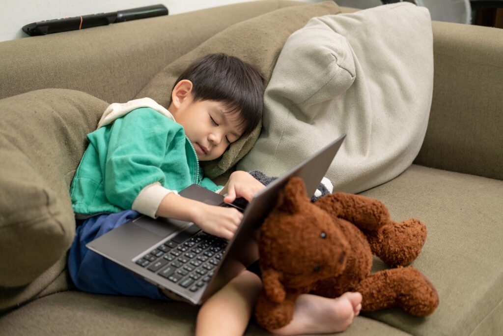 boy sleeping while studying online on a laptop.